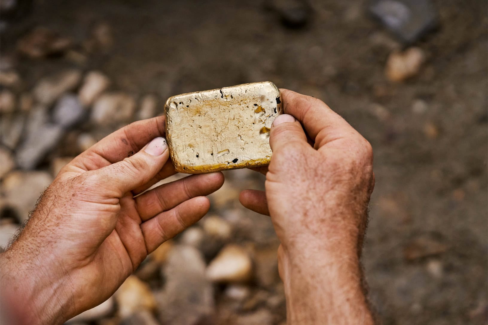 Close up photo of two hands holding a small bar of gold
