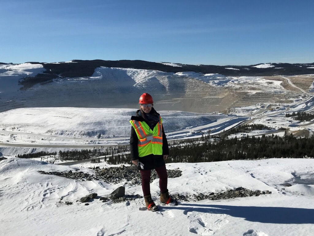 Consumerism & the mining industry: part 2 1 Elizabeth Freele stands smiling in front of a snowy open-pit mine. She is dressed in full PPE