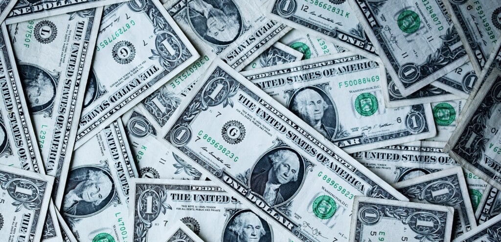 Consumerism & the mining industry: part 1 2 a large pile of dollar bills, viewed from above