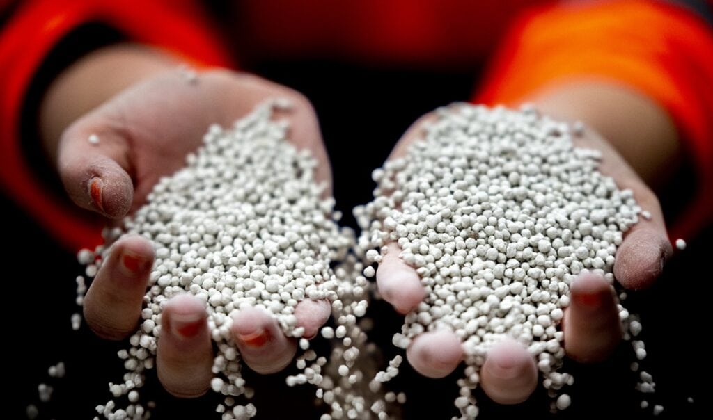 Newsletter October 2026 - Operating models. The next step in mining’s digital transformation 4 Close-up of hands holding small white mineral granules, highlighting their texture and size, suitable for industrial applications and mineral extraction.