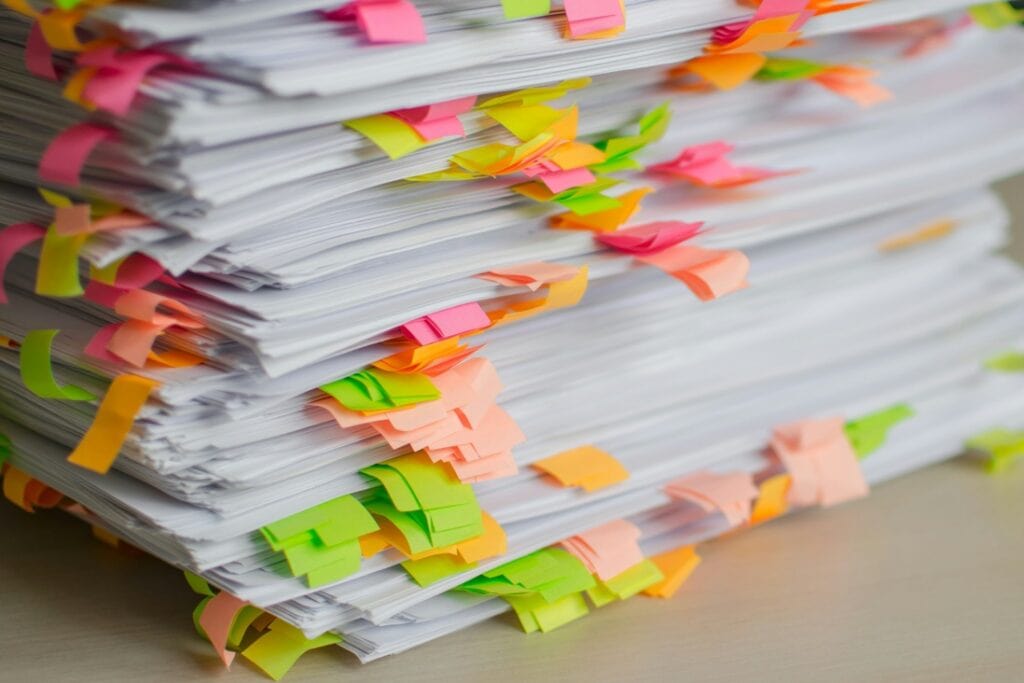 Spotlight: The cost of proving a tonne of metal 2 A large stack of paper documents filled with colourful sticky notes and tabs, in the review into the hidden cost of fragmented sustainability data